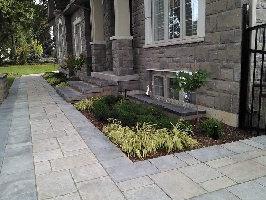 Finished landscaping and clear window well cover at a stone home